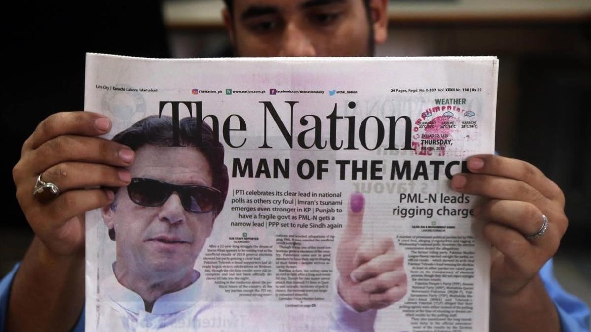 Un ciudadano lee un periodico que lleva a su portada una foto del exjugador de criquet Imran Khan  lider del partido Pakistan Tehreek-i-Insaf  .PTI