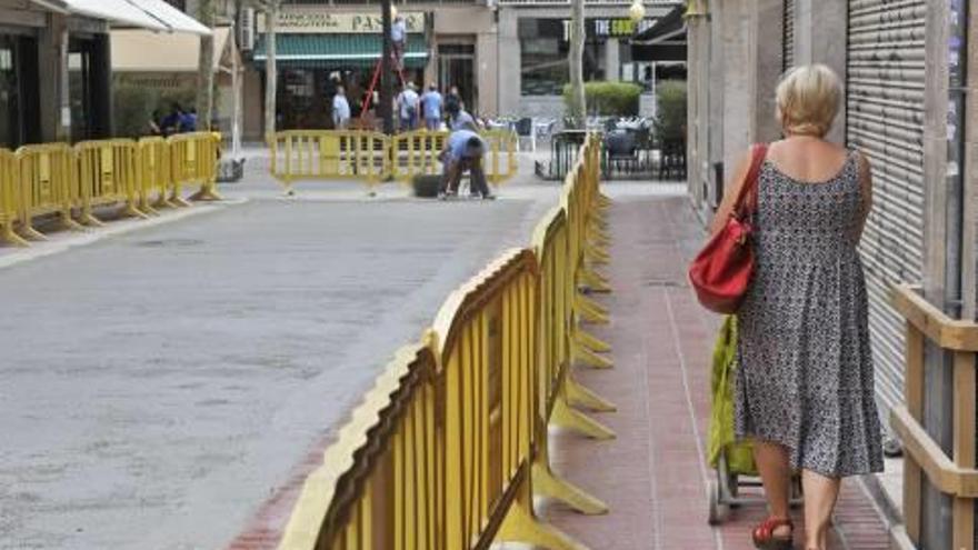 Una mujer pasa ayer por la calle de Les Ànimes mientras los operarios trabajan en su adecuación.