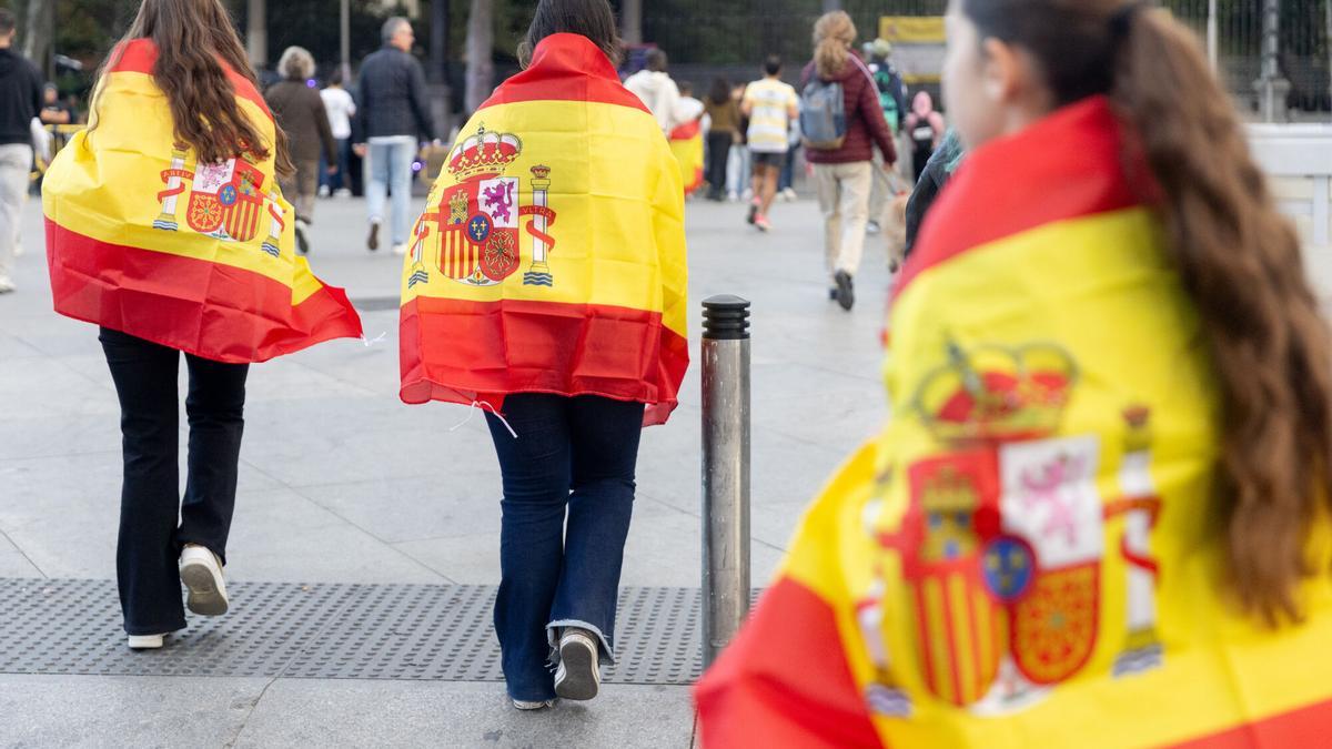Público portando banderas de España antes del acto solemne de homenaje a la bandera nacional y desfile militar por el 12 de octubre, Día de la Hispanidad, en la Plaza de Cánovas del Castillo, a 12 de octubre de 2025, en Madrid (España). Los actos comienzan con el izado de bandera y van seguidos del homenaje a los que dieron la vida por el país. Posteriormente, comienzan los desfiles militares aéreos y terrestres. En total, 3.847 efectivos de las Fuerzas Armadas, las Fuerzas y Cuerpos de Seguridad del Estado y otras instituciones del Estado participarán en el desfile, junto a 229 caballos, 6 perros, 45 aviones y 29 helicópteros. 12 OCTUBRE 2025;DESFILE MILITAR;DÍA DE LA HISPANIDAD Eduardo Parra / Europa Press 12/10/2025. Eduardo Parra;