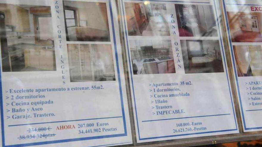 Carteles de ofertas de pisos en venta en una inmobiliaria de A Coruña.