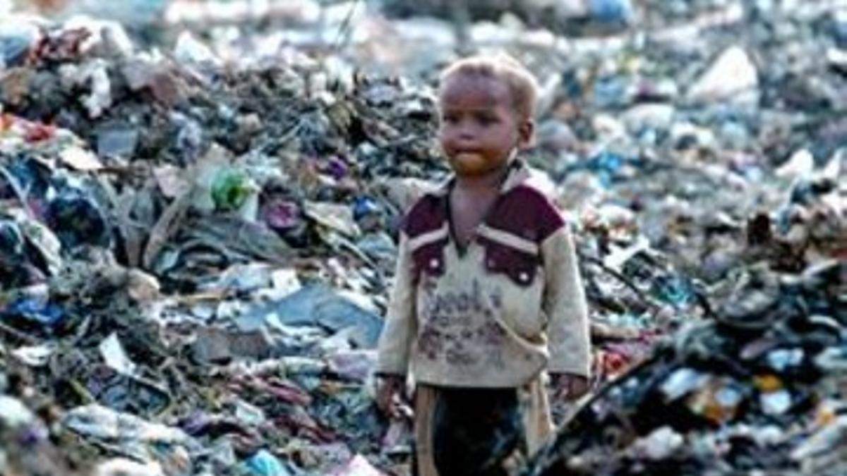 Un niño indio, hijo de un trapero, rodeado de basura en Nueva Delhi.