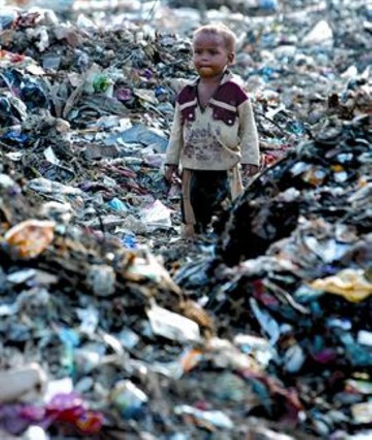 Un nen indi, fill d’un drapaire, envoltat d’escombraries a Nova Delhi.