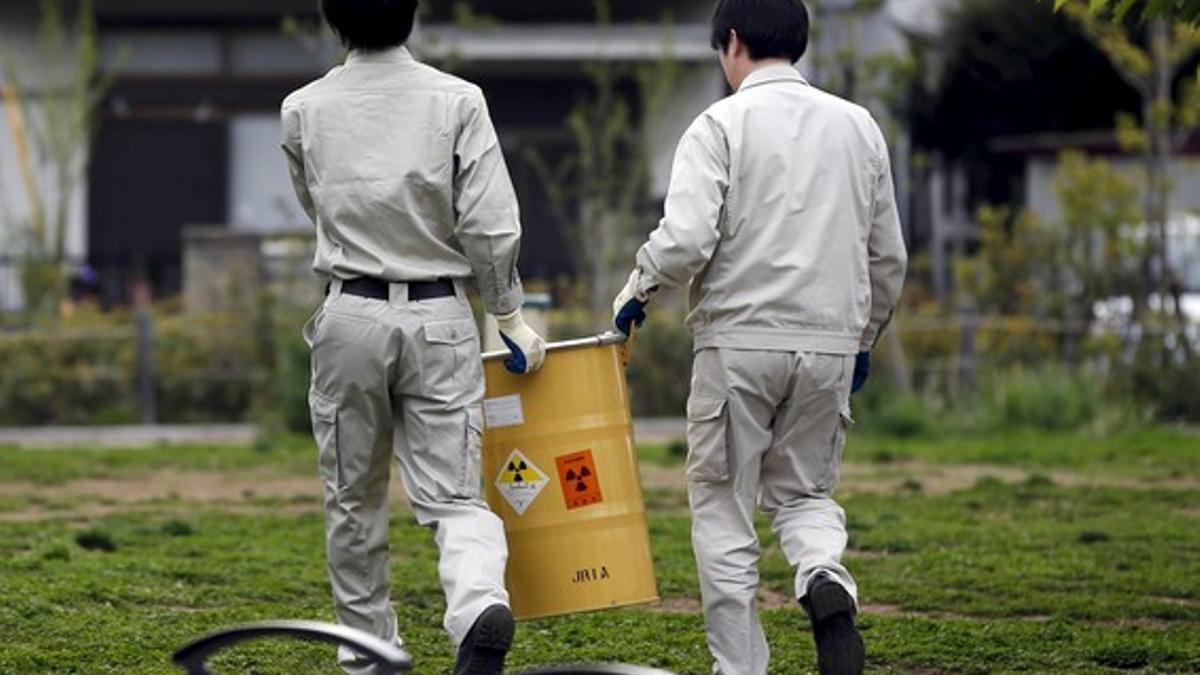 Workers of Tokyo's Toshima ward office carry away a container holding a fragment of an unknown object after it was dug up from the ground near playground equipment at a park in Toshima ward