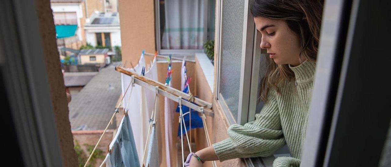 Un a joven tiende la ropa en su vivienda.