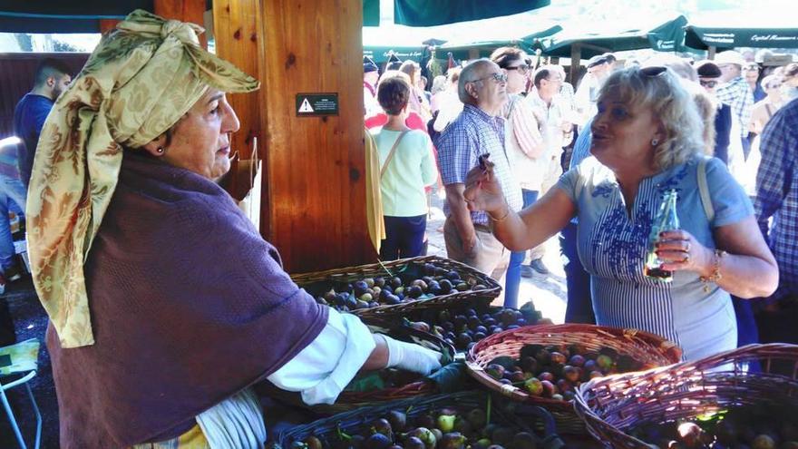 Loli Díaz conversa con una clienta en el puesto que la asociación puso para vender figos frescos, ayer, en la feria de Rozaes.