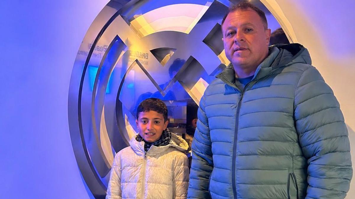 Alonso Urquía posa junto a su entrenador en el Herbania de Fuerteventura, Nauzet Cruz, junto al escudo del Real Madrid.