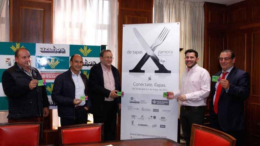 Los organizadores de la feria de tapa posan junto al cartel de la décima edición.