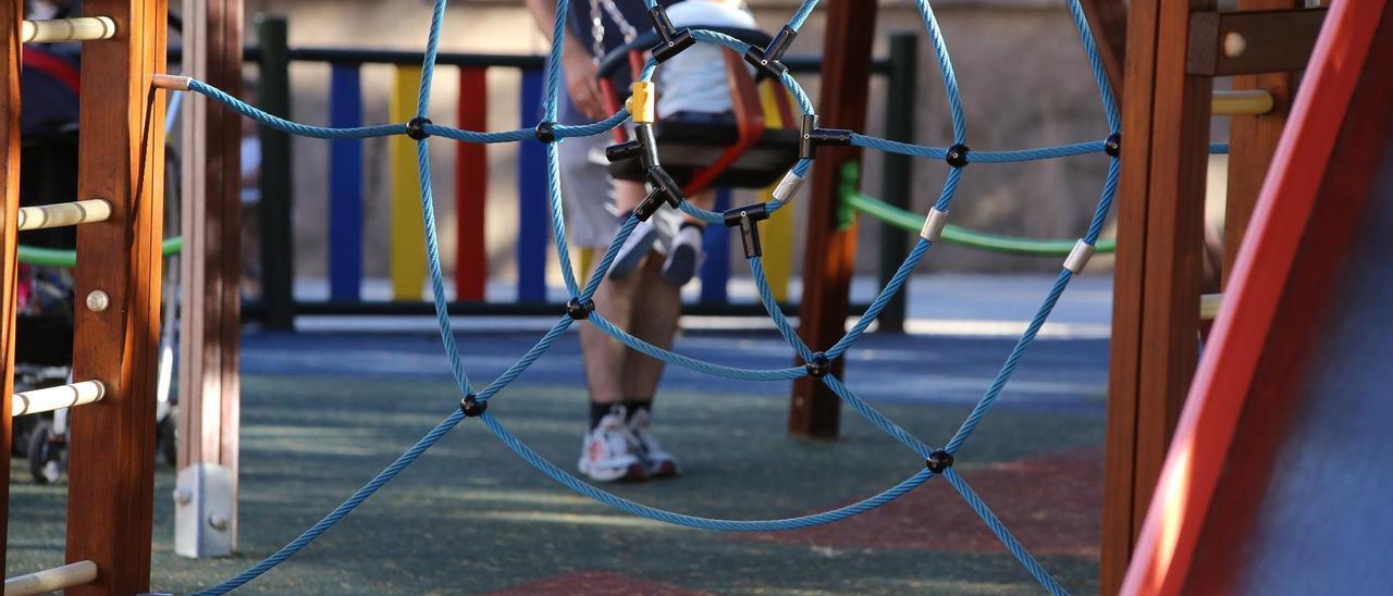 UN PADRE Y SU HIJO, EN UN COLUMPIO DE UN PARQUE INFANTIL.