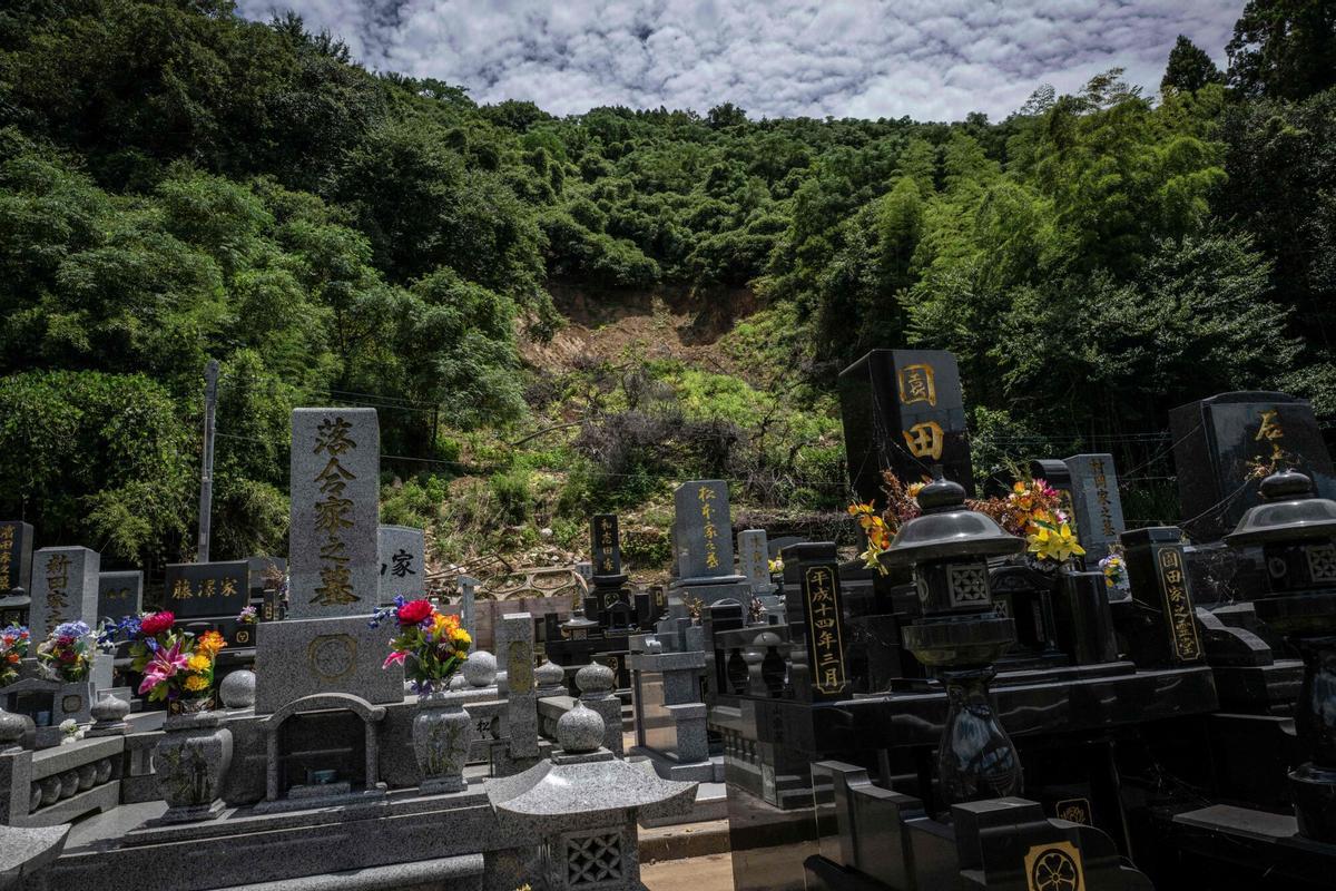 Un deslizamiento de tierra se ve detrás de las lápidas en Yatsushiro, prefectura de Kumamoto, el 29 de julio de 2026, después de que un terremoto sacudió el suroeste de Japón el día anterior. (Foto de Yuichi YAMAZAKI / AFP)