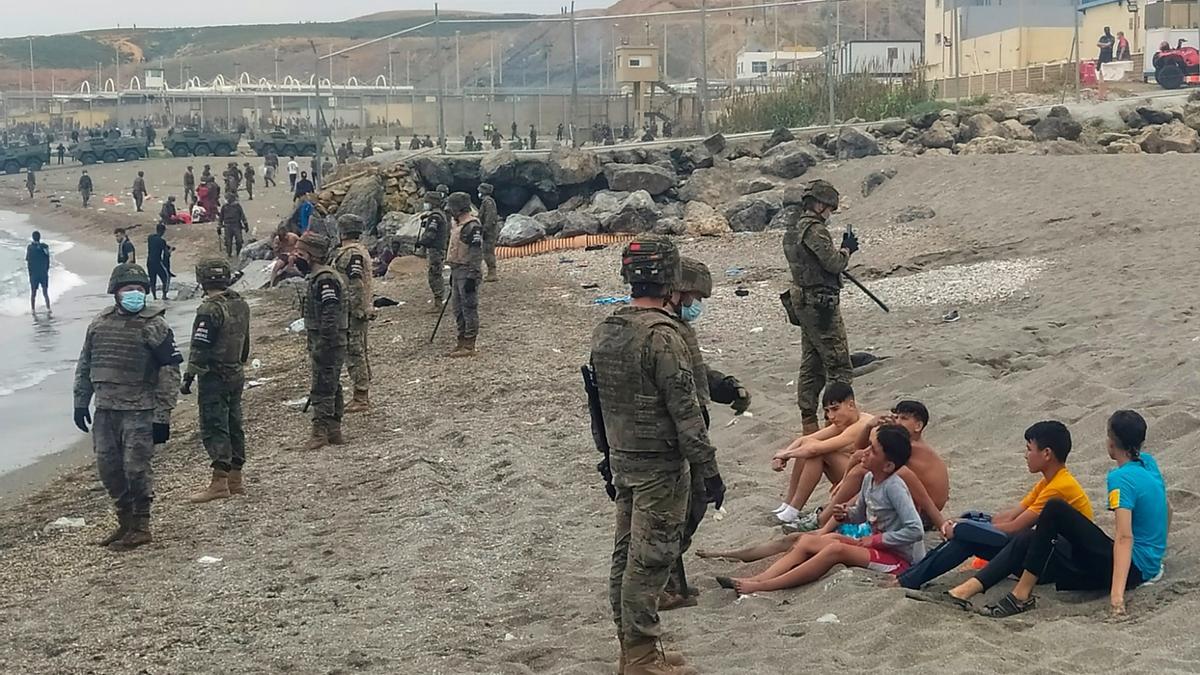 Militares españoles junto a inmigrantes en la costa.