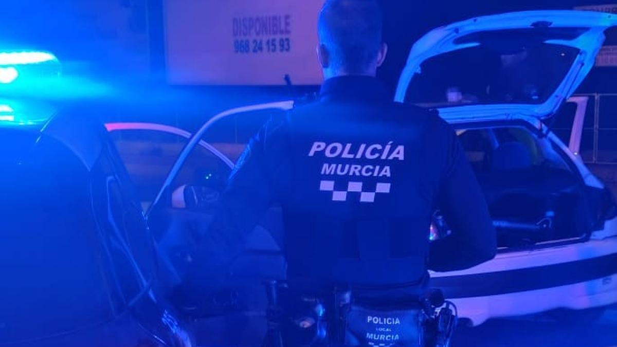 Un policía local de Murcia junto a su vehículo.