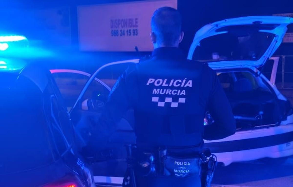 Un policía local de Murcia junto a su vehículo.