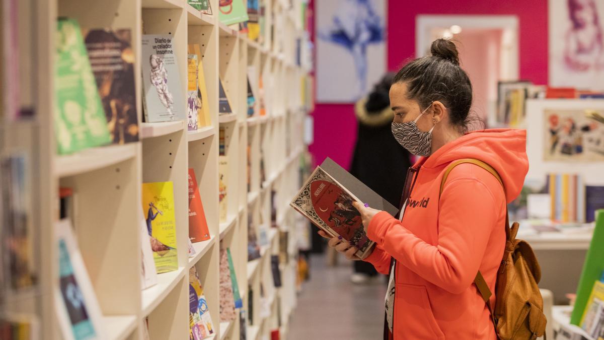 Una clienta hojea un ejemplar en una librería.