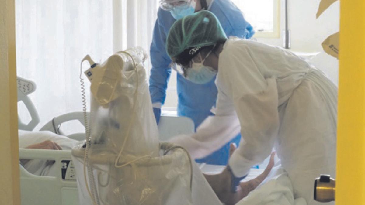 Dues professionals sanitàries amb un pacient en una habitació de l’Hospital Trueta. | ICS GIRONA/ARXIU