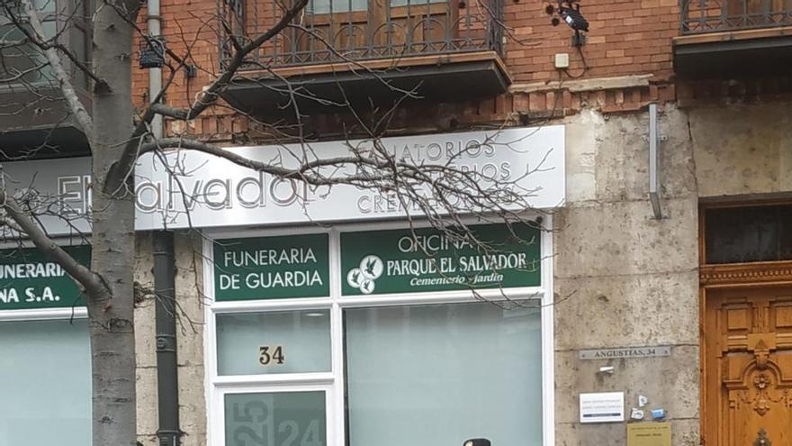 Un policía, delante de la puerta de una oficina de la funeraria.