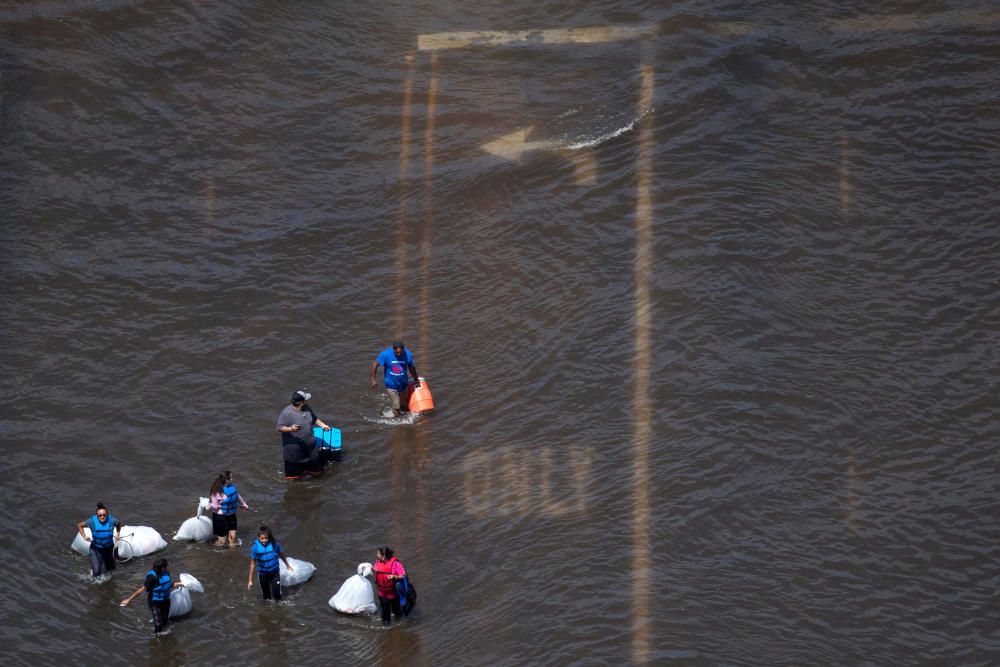 A group of people carry supplies through flood ...