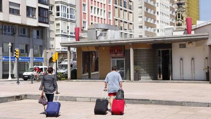 Dos turistas cruzan con sus maletas por la gijonesa zona del Náutico.