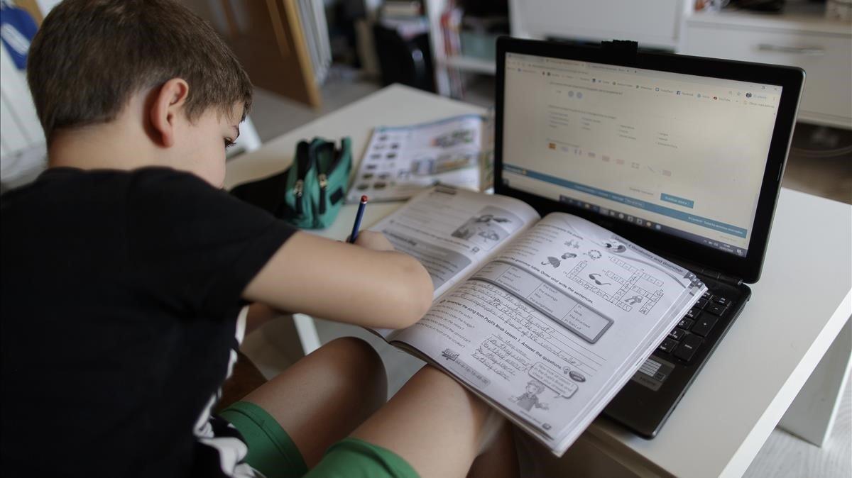 Un niño realiza sus deberes con un portátil en su casa, durante el confinamento. 