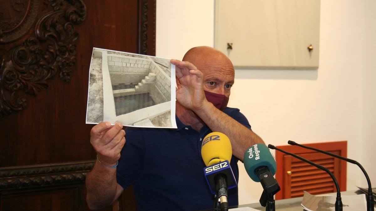 Pedro Sosa muestra una fotografía con el muro que se ha construido en el cauce