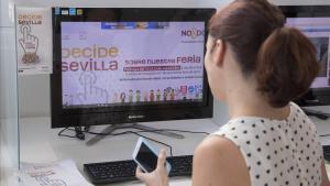 Una empleada del Ayuntamiento de Sevilla ante la web abierta para votar sobre la duración de la Feria de Abril.