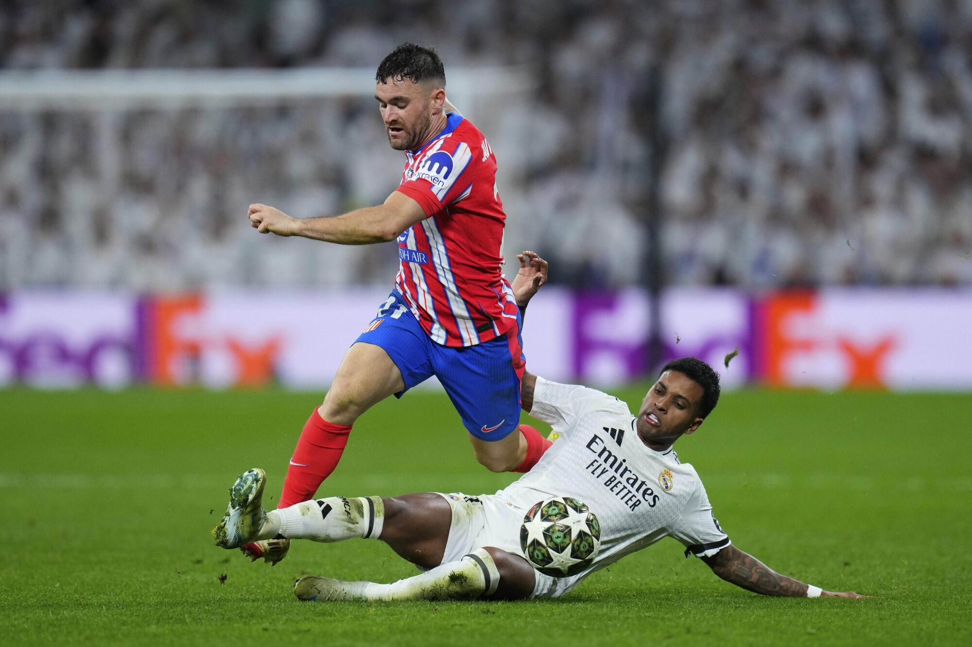 Atletico Madrid's Javi Galan, left, is challenged by Real Madrid's Rodrygo during the Champions League round of 16 first leg soccer match between Real Madrid and Atletico Madrid at the Bernebeu stadium in Madrid, Spain, Tuesday, March 4, 2025. (AP Photo/Manu Fernandez). EDITORIAL USE ONLY / ONLY ITALY AND SPAIN