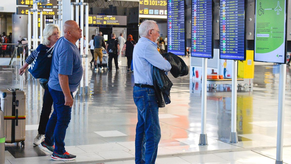 Turistas mirando las pantallas de información de vuelos en el aeropuerto de Gran Canaria.