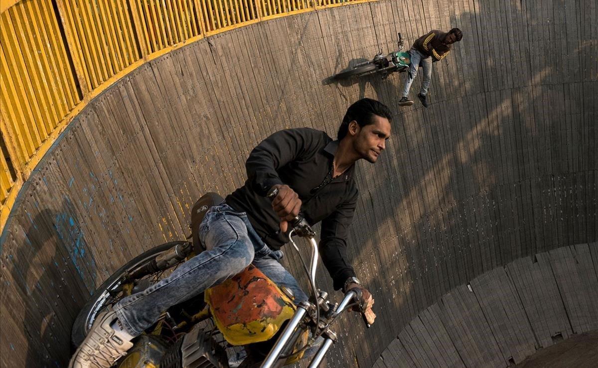 En esta foto tomada el 27 de enero de 2019, dos pilotos indios realizan acrobacias en motocicletas durante el festival Kumbh Mela, en Allahabad. Los pilotos confían en la fricción y la fuerza centrífuga para mantener el agarre en las paredes verticales.