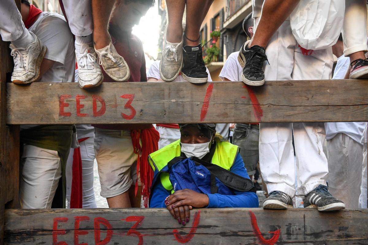 Un participante observa desde detrás de una valla durante el encierro de las fiestas de San Fermín en Pamplona.