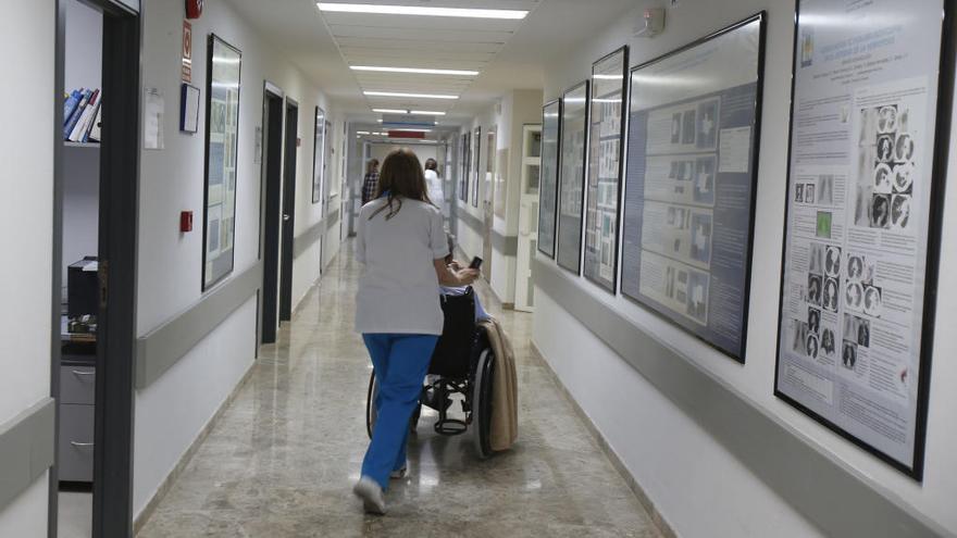 Una celadora tralsada a una paciente en el hospital de Alzira.