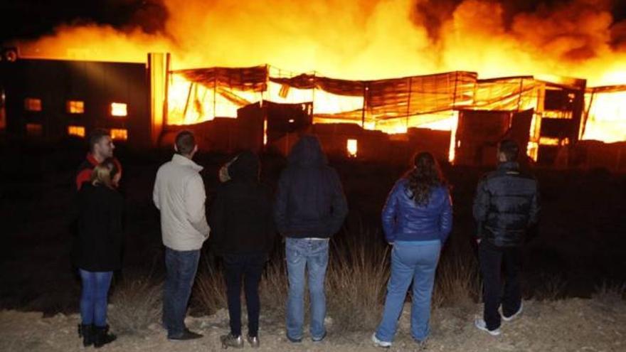 Varias personas observan cómo el fuego devasta la nave de Liwe Española.