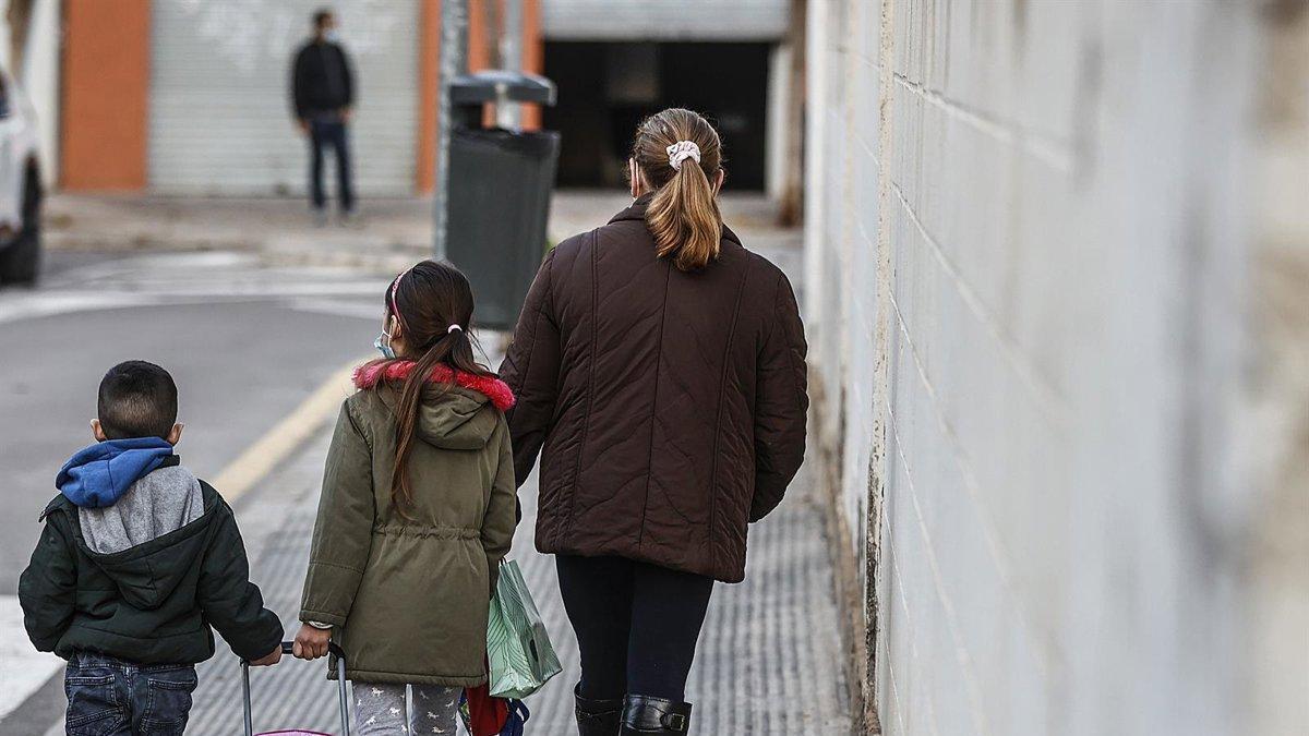 Una dona acompanya dos infants pel carrer, en una imatge que il·lustra el pes quotidià de les cures i de la criança