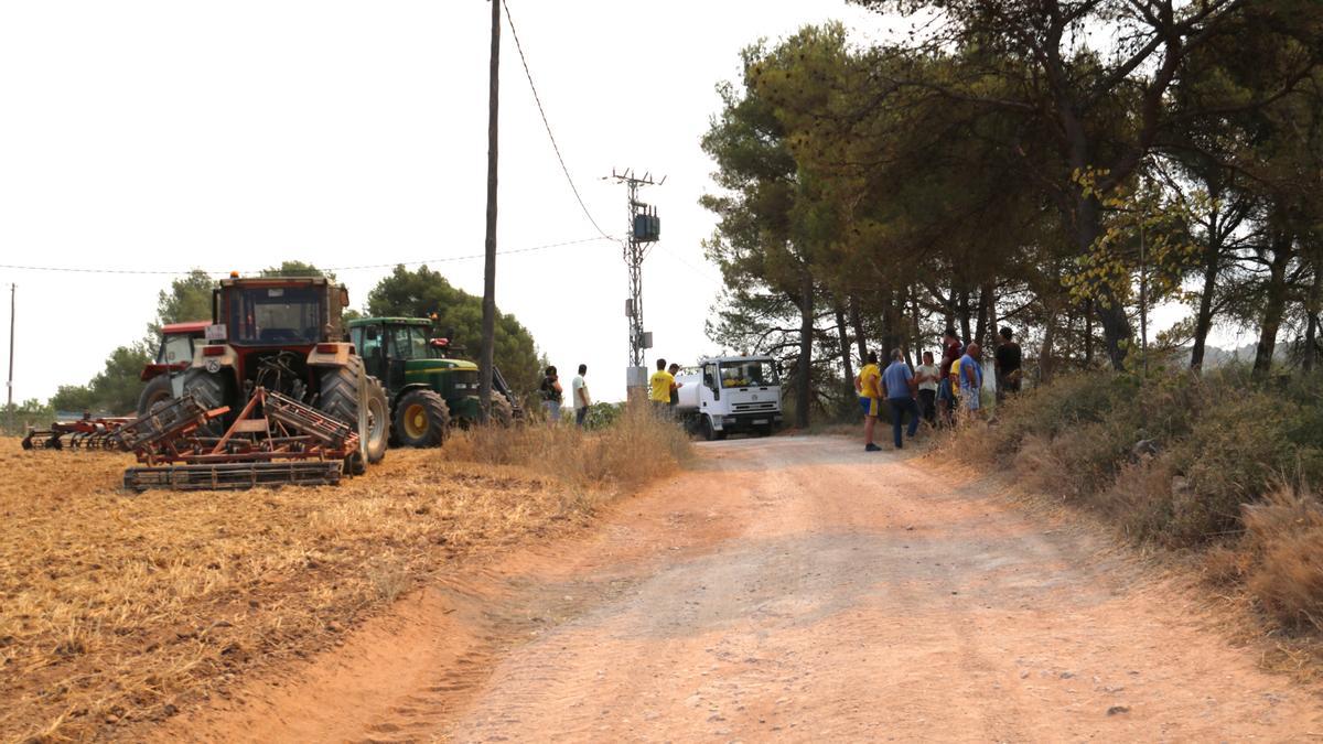 Un grup de pagesos seguint l&#039;evolució del foc prop dels seus tractors a Sant Martí de Tous