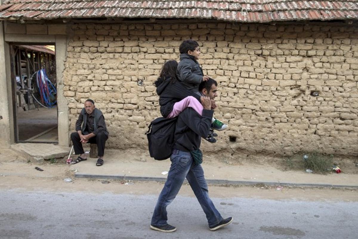 Un refugiado sirio camina por Miratovac con un niño en sus hombros.