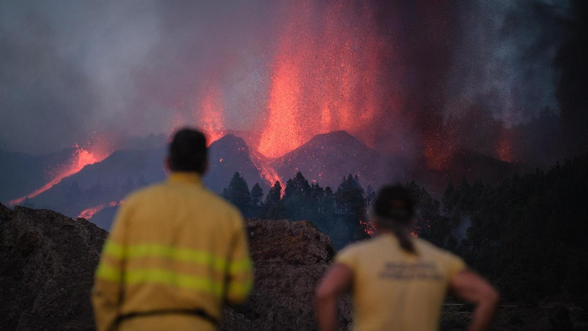 Imagen de archivo en el que se observan a varios operarios de las brigadas forestales contemplando la erupción del Tajogaite.
