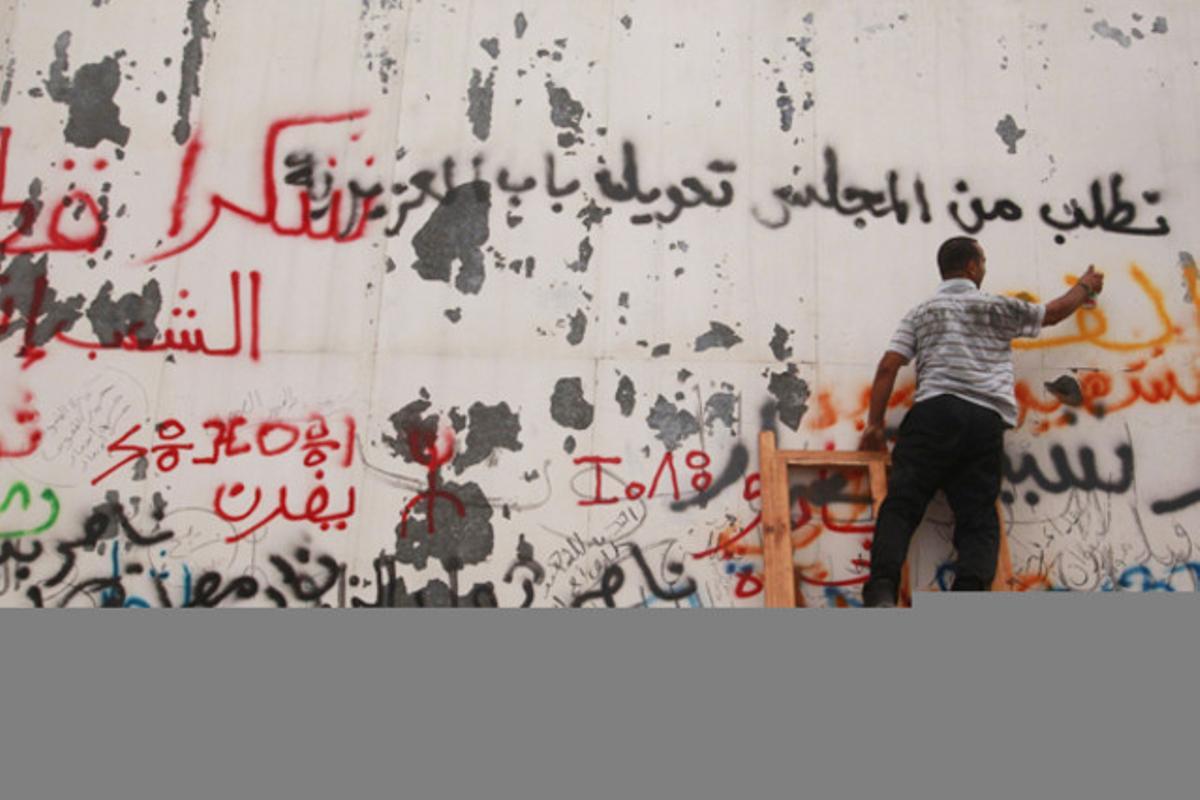 Un opositor de Gaddafi escriu consignes en contra del dictador al mur exterior del complex de Bab al-Azizia a Trípoli (Líbia).
