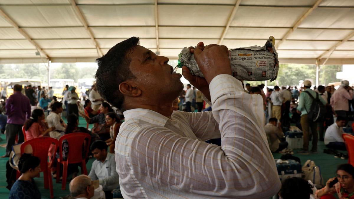 Un trabajador del colegio electoral bebe agua con la camisa pegada al cuerpo en mitad de la ola de calor