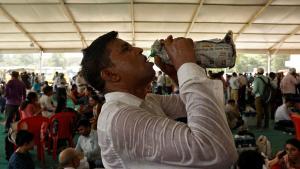 Un trabajador del colegio electoral bebe agua con la camisa pegada al cuerpo en mitad de la ola de calor