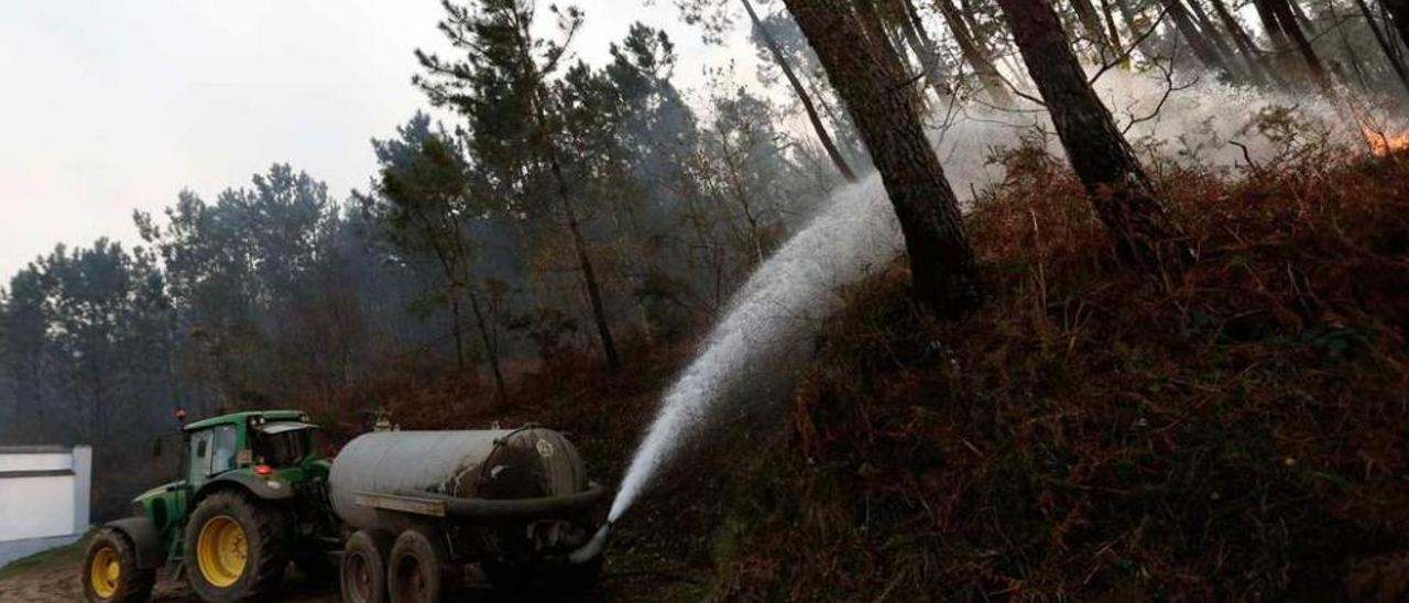 Unos vecinos de La Veguina luchan contra el fuego con una cisterna de agua.