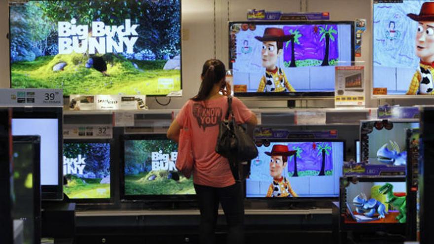 Una chica observa varias televisiones en un centro comercial.