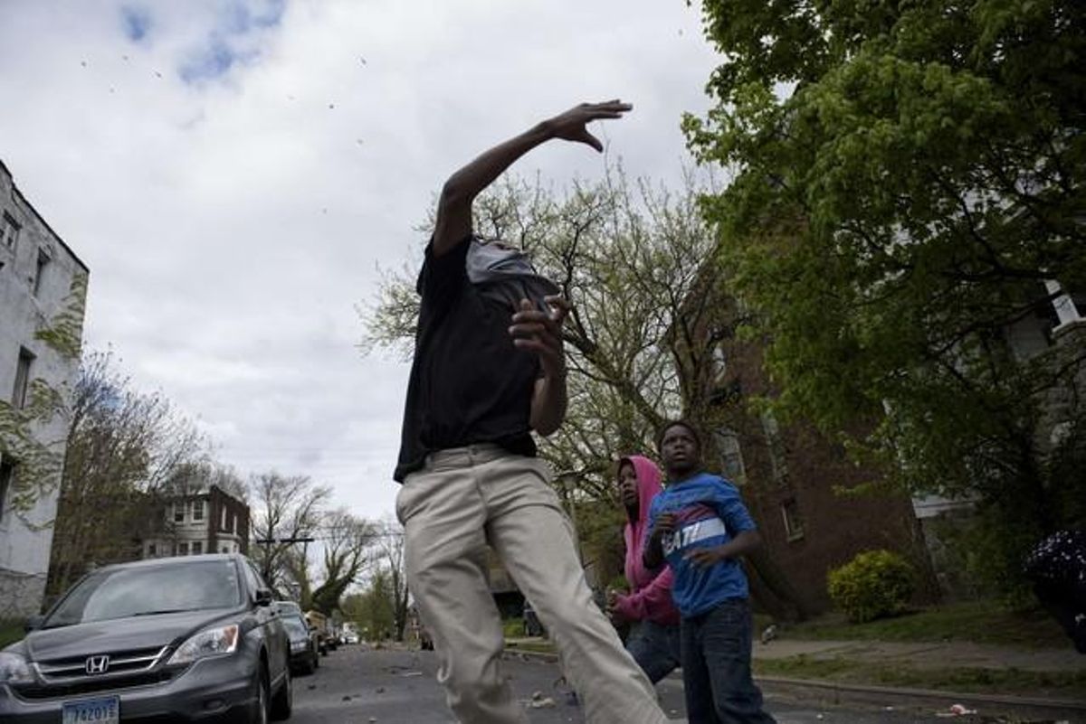 Un jove de Baltimore llança una pedra als agents.
