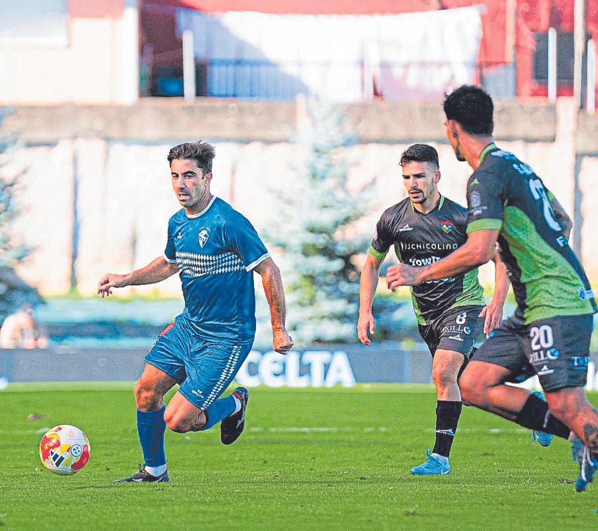 Antón conduce un balón perseguido por dos rivales.