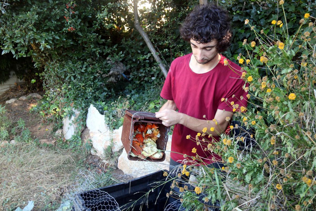 El veí de Girona Marcel Llavero abocant restes orgàniques al compostador que té al jardí de casa seva al barri de Montjuïc de Girona