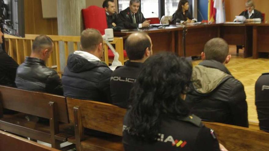 Los tres acusados, de espaldas y escoltados por policías nacionales, ayer en la Audiencia viguesa. // A.I.