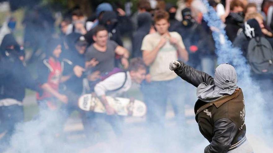 Un manifestante enmascarado se deshace de un bote policial de gas en la ciudad de Nantes. // Reuters