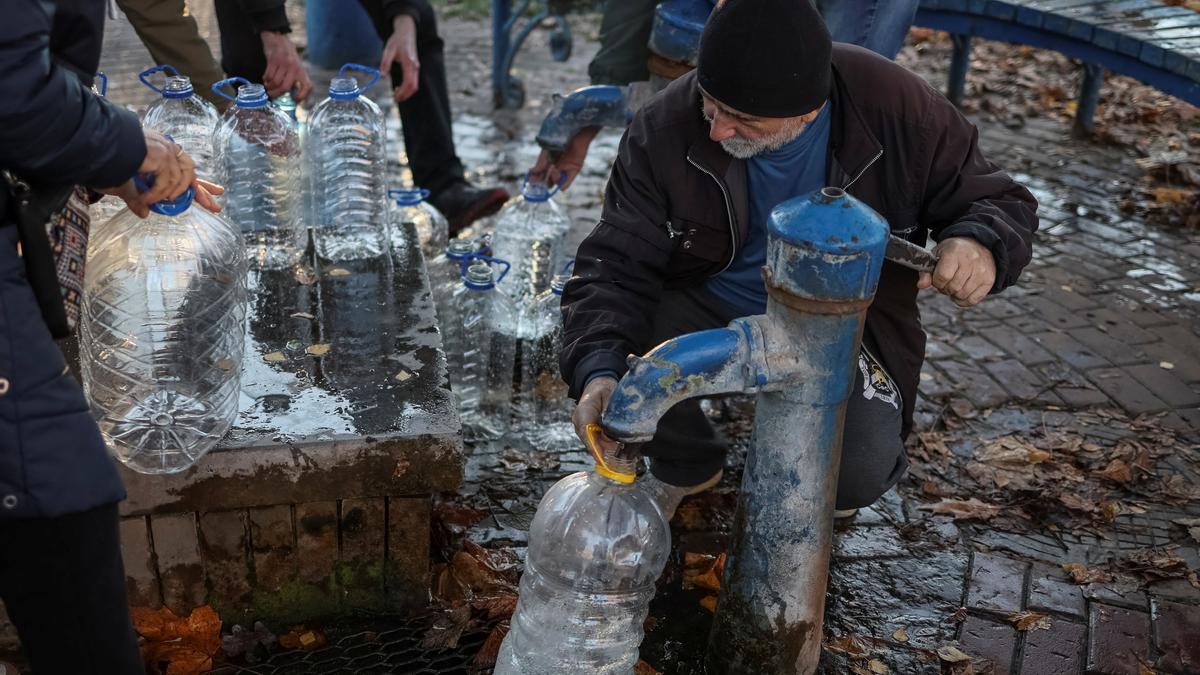 Un hombre aprovisionándose llenando una botella de agua en Kiev.