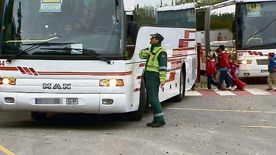 Un guardia civil charla con el conductor de un autobús escolar.