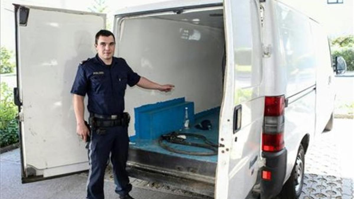 Un agente austriaco muestra la camioneta en la que viajaban los tres niños hallados en estado grave, este sábado, en Braunau (Austria).