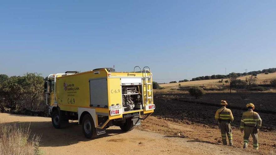 Dos bomberos observan una de las zonas afectadas por el incendio en Vega de Tera.