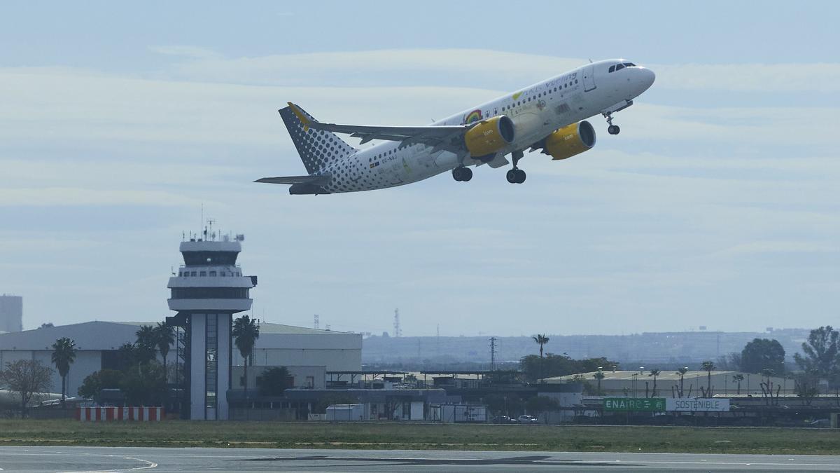 Un avión despega y al fondo la torre de control en el aeropuerto de Sevilla.