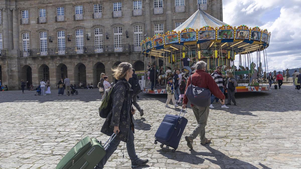 Dos turistas con sus maletas en la Praza do Obradoiro, en el casco histórico de Santiago